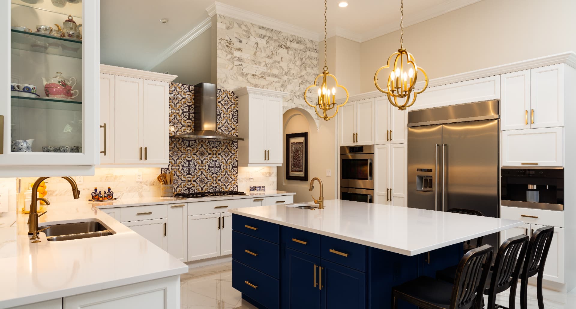 Luxury kitchen with white cabinets, blue island, and gold fixtures